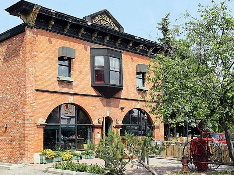 A restored red-brick heritage building with arched windows and a garden in Inglewood