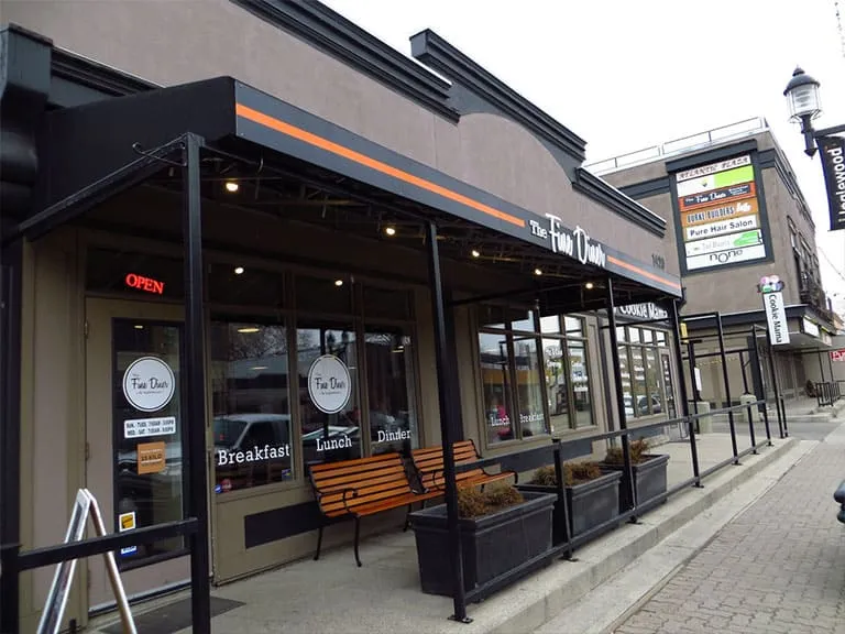 A café with a covered patio and wooden benches on an Inglewood street
