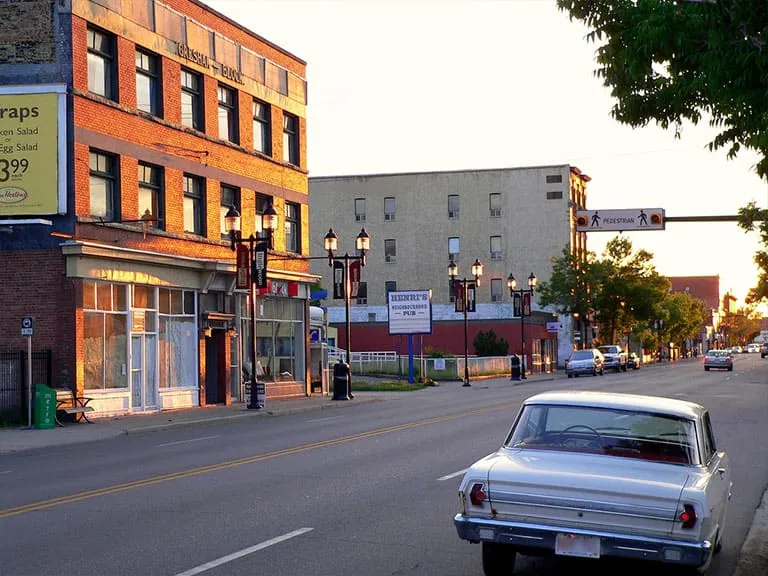 A classic car on 9th Avenue at sunset, with historic brick buildings along the street